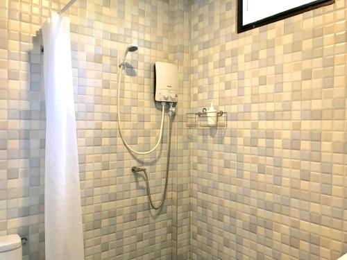 a shower in a bathroom with white tiled walls at Kiri Tawan in Baan Tai