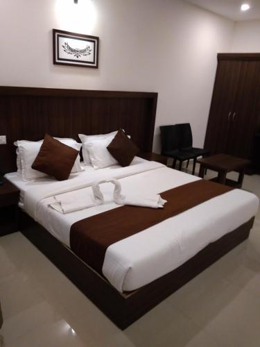 a bedroom with a large bed with white and brown sheets at Highrange Plaza in Thekkady