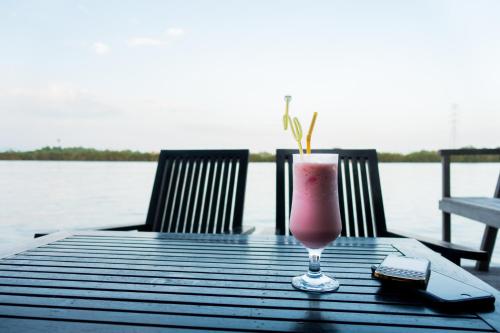 una bebida sentada en una mesa junto a un lago en Bamboo Bungalow, en Kampot