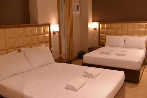 two beds in a hotel room with towels on them at Robertson Hotel in Naga