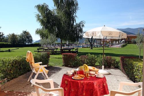 a picnic table with a red table cloth and a white umbrella at Hotel Residence La Pertica in Tremosine Sul Garda