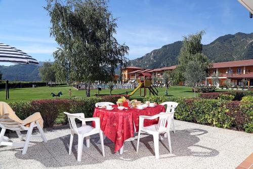 a table with a red table cloth and white chairs at Hotel Residence La Pertica in Tremosine Sul Garda
