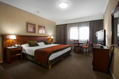 a hotel room with a bed and a television at Tucuman Center Suites&Business in San Miguel de Tucumán