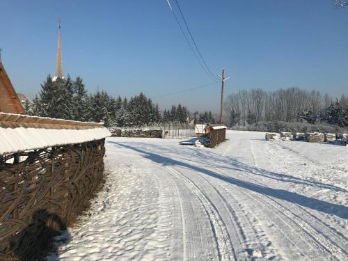 a snow covered road with a fence and trees at "Plai cu Peri" in Săpînţa