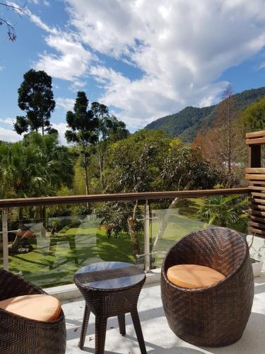 a patio with two chairs and a table on a balcony at Around The Tree Manor in Shitan