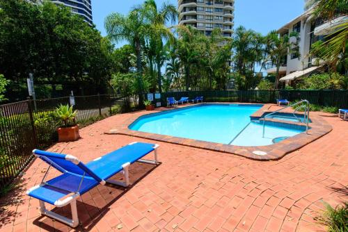 a swimming pool with a blue lounge chair and a table at Broadwater Shores Waterfront Apartments in Gold Coast