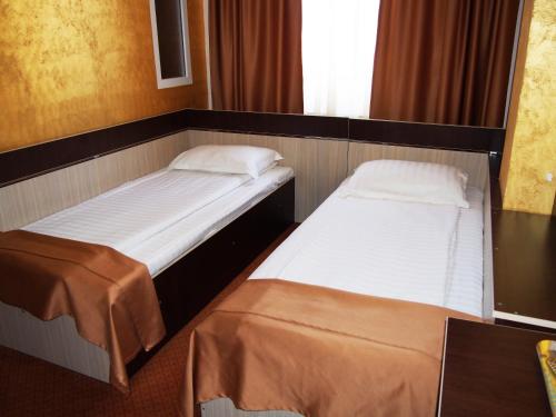 two beds in a small room withermottermottermott at Asia Hotel in Târgu Jiu