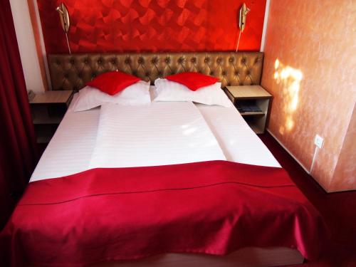 a red and white bed with red sheets and pillows at Asia Hotel in Târgu Jiu