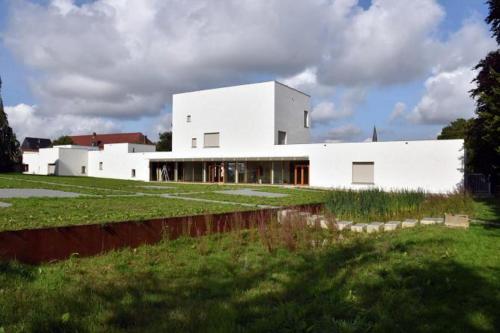 un grand bâtiment blanc dans un champ d'herbe dans l'établissement B&B La demeure du Papillon, à Mouscron