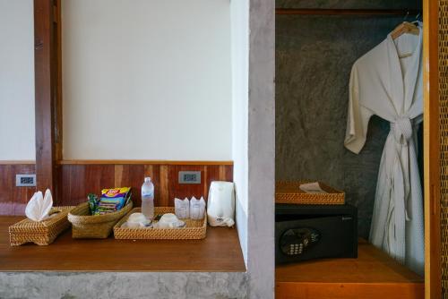a shelf with baskets of towels and a dress on a wall at Sai Daeng Resort in Koh Tao