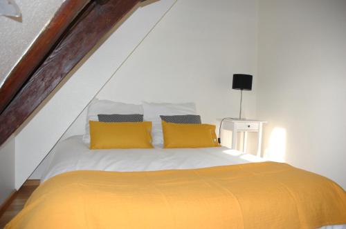 1 dormitorio con 1 cama con almohadas amarillas en appartement à Colmar en Colmar