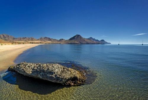a rock in the water next to a beach at Casa Glorieta en Villa de Nijar con piscina in Níjar