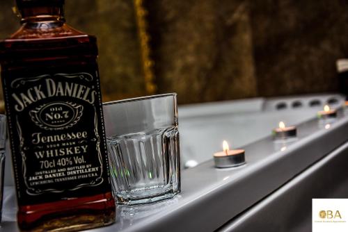 a bottle of whisky next to a glass and candles at Central Business Apartments Jacuzzi in Belgrade