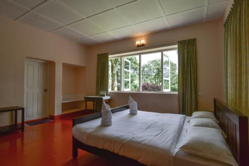 a bedroom with a large bed and a window at Manalar in Gūdalūr