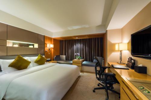 a hotel room with a large bed and a desk at Grand Mercure Xiamen Downtown-Free Welcome Fruit & Metro Station in Xiamen