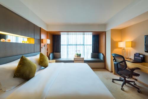 a hotel room with a large bed and a desk at Grand Mercure Xiamen Downtown-Free Welcome Fruit & Metro Station in Xiamen