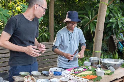 two men standing in front of a table with food at Soothing Stay Backpackers Inn in Tianwei