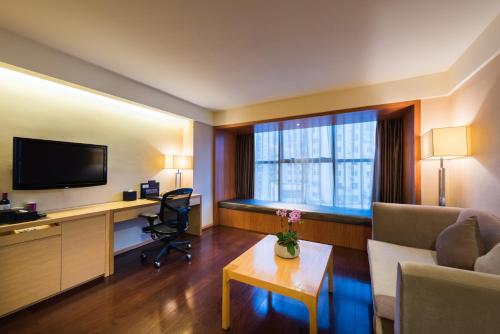 a hotel room with a desk and a television at Grand Mercure Xiamen Downtown-Free Welcome Fruit & Metro Station in Xiamen