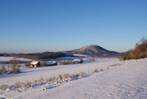 a snow covered field with a mountain in the background at Guest House K74 in Jablonné v Podještědí