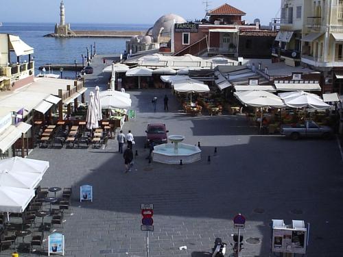 a street with white umbrellas and chairs and the ocean at Pia Rooms in Chania