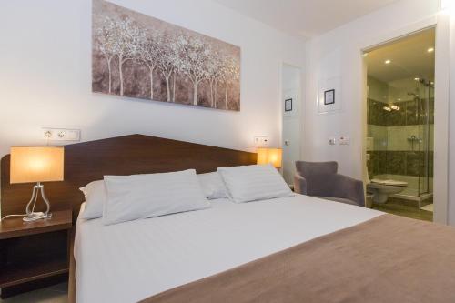 a bedroom with a large white bed and a bathroom at Villa Four Winds II in Dubrovnik