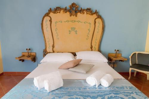 a bed with a large headboard and two pillows at Palazzo Maria in Cefalù