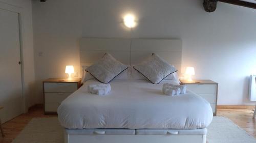 um quarto com uma grande cama branca e 2 candeeiros em Casa Campacinas Casas Vacacional con vistas del rio em O Carballo