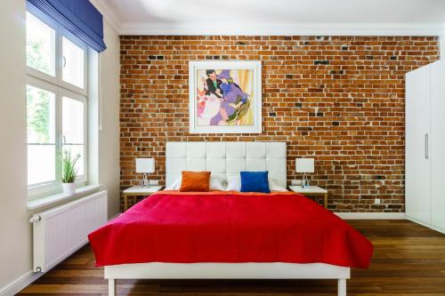 a bedroom with a red bed with a brick wall at Sanhaus Apartments - ul HAFFNERA i okolice - 3-5 minut od plaży i deptaka in Sopot