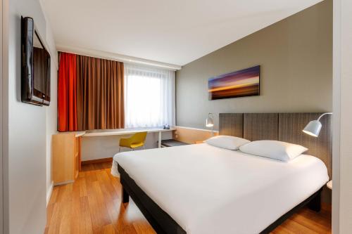 um quarto de hotel com uma grande cama branca e uma janela em ibis Bremen City em Bremen