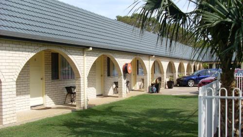 a building with arches and a car parked in a parking lot at Sunshine Coast Airport Motel in Marcoola