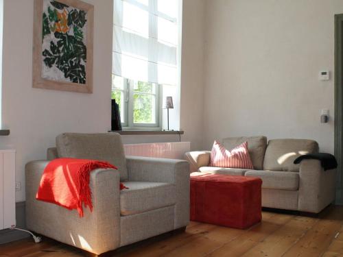 a living room with two couches and a red ottoman at Ferienwohnung in Steffenshagen mit Garten in Steffenshagen