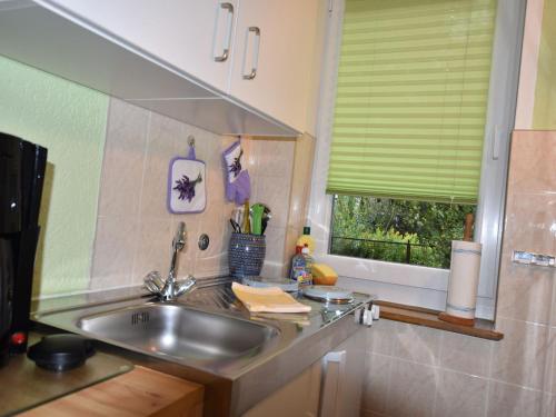 uma cozinha com um lavatório de aço inoxidável e uma janela em Quaint Bungalow in Reddelich near Baltic Sea Coast em Reddelich