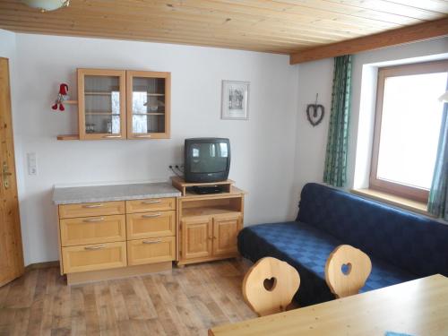 a living room with a blue couch and a tv at Honsnhof in Tux