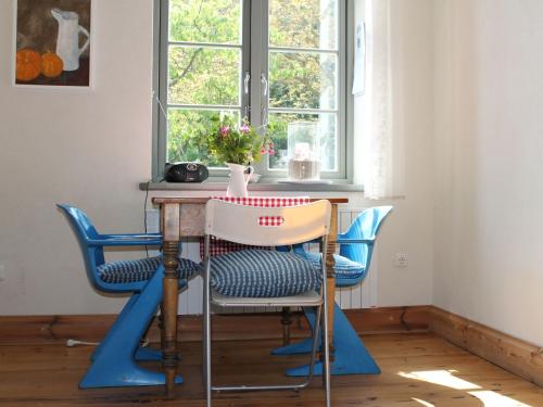 a dining room table with blue chairs in front of a window at Kleine Ferienwohnung in Steffenshagen mit Garten in Steffenshagen