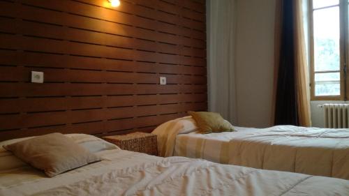 a bedroom with two beds and a wooden wall at Hôtel de Valdeblore in Valdeblore