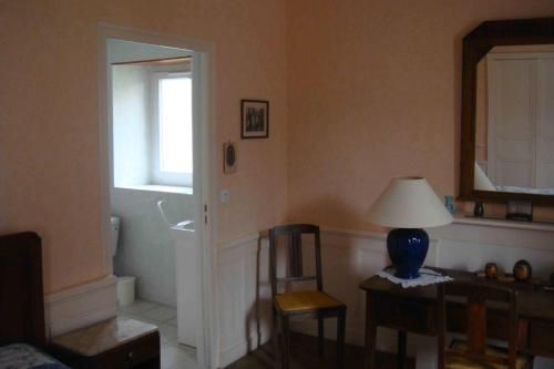 sala de estar con mesa, sillas y lámpara en Le Verger de Mathurin, en Le Molay-Littry