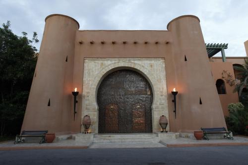 un edificio con una gran puerta de madera con dos bancos en El Ksar Resort & Thalasso, en Sousse
