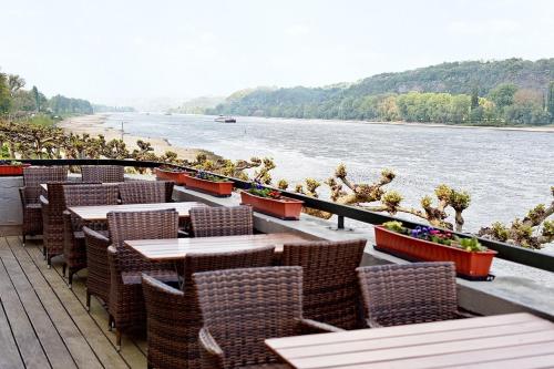a row of tables and chairs next to a river at Rheinhotel Vier Jahreszeiten Bad Breisig in Bad Breisig