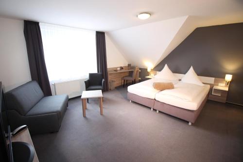 a bedroom with a bed and a desk and a chair at Hotel Restaurant Jägerhof in Braunschweig