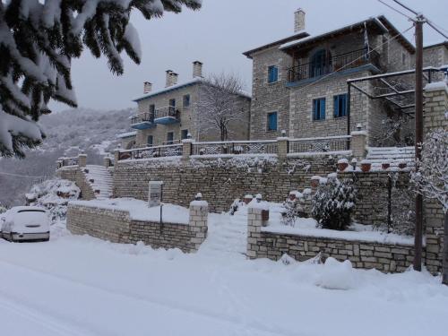 a house with a car parked in the snow at Hotel Ladias in Monodendri