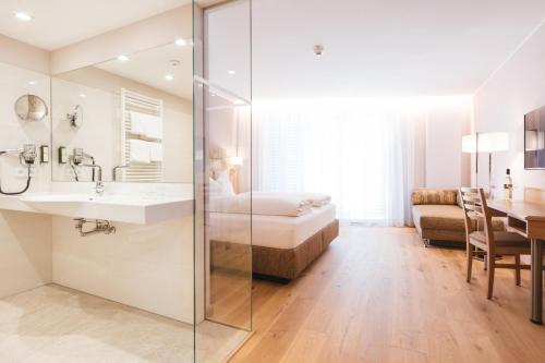 a bathroom with a sink and a bedroom with a bed at Hotel am Marktplatz - Landgasthof Wratschko - Gamlitz in Gamlitz