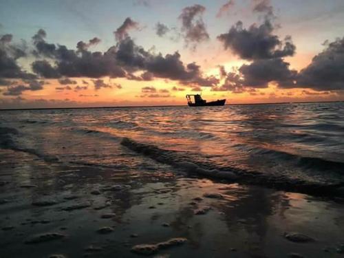 a boat sitting in the ocean at sunset at A 2 passos do paraíso in Rio Tinto