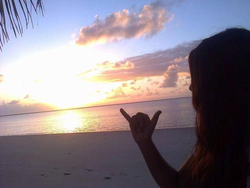 a woman standing on the beach pointing at the sunset at A 2 passos do paraíso in Rio Tinto