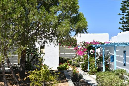 a white house with flowers in the yard at Surfing Beach Village Paros in Santa Maria