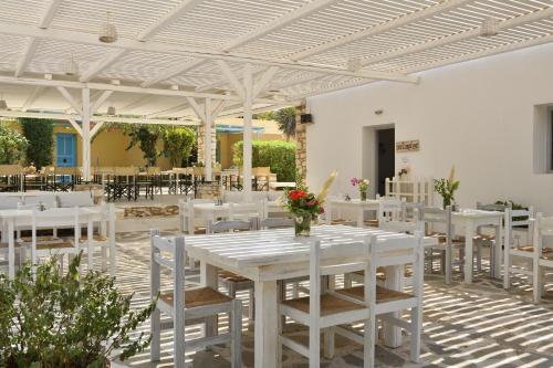 a white dining room with white tables and chairs at Surfing Beach Village Paros in Santa Maria