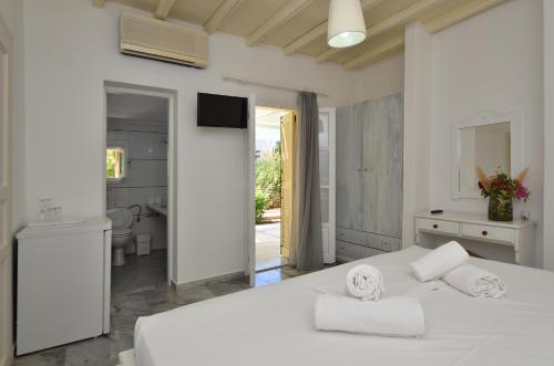 a white bedroom with a white bed and a bathroom at Surfing Beach Village Paros in Santa Maria