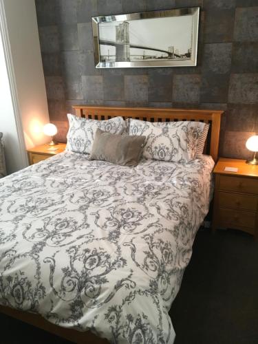 1 dormitorio con 1 cama, espejo y 2 lámparas en Ashleigh Lodge, en Hunstanton