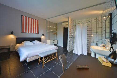 a bedroom with a bed and a bathroom with a sink at Logis - Hotel Restaurant La Mire in Vierzon