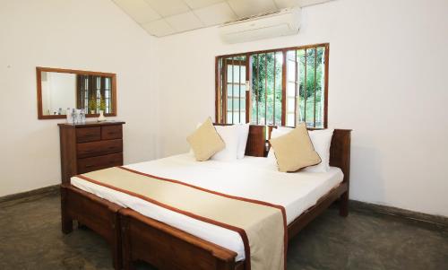 1 dormitorio con 1 cama con sábanas blancas y 2 ventanas en Villa Indrasiriya, en Ahangama