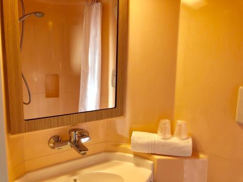 a bathroom with a sink and a mirror and a toilet at Premiere Classe Perpignan Sud in Perpignan